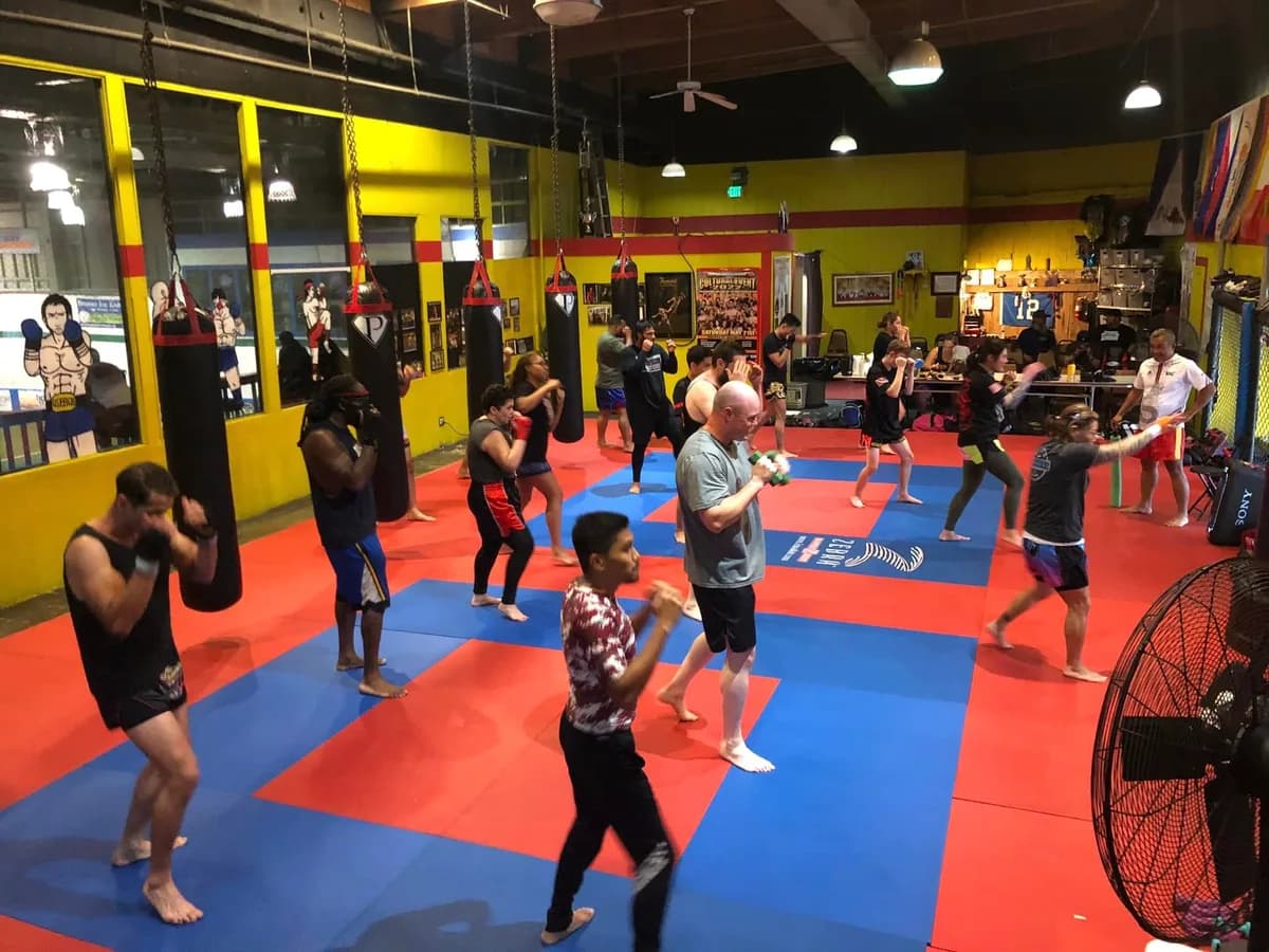 A full evening class shadow boxing on the mats between the heavy bags