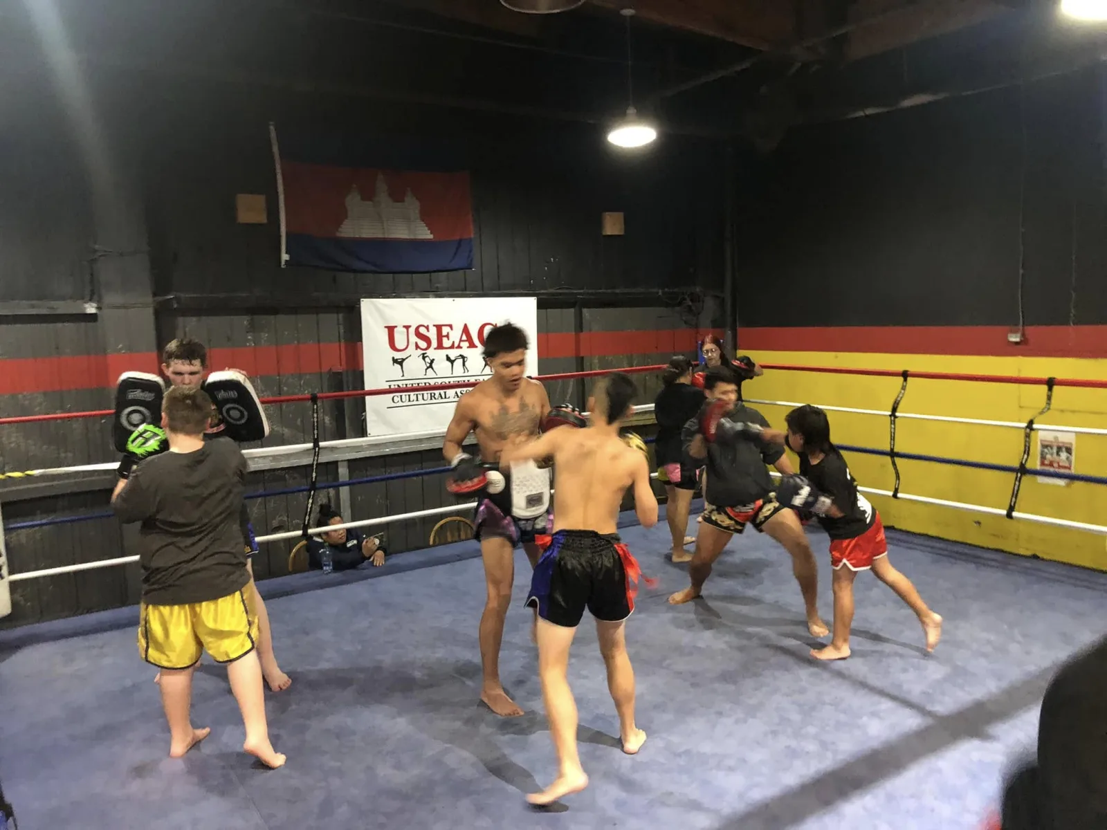 Fighters working pads inside the ring, beneath the Cambodian flag and the USEACA banner