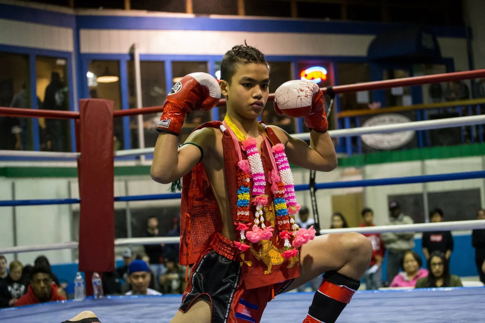 Young fighter performing the Wai Kru before a bout, wearing ceremonial garlands