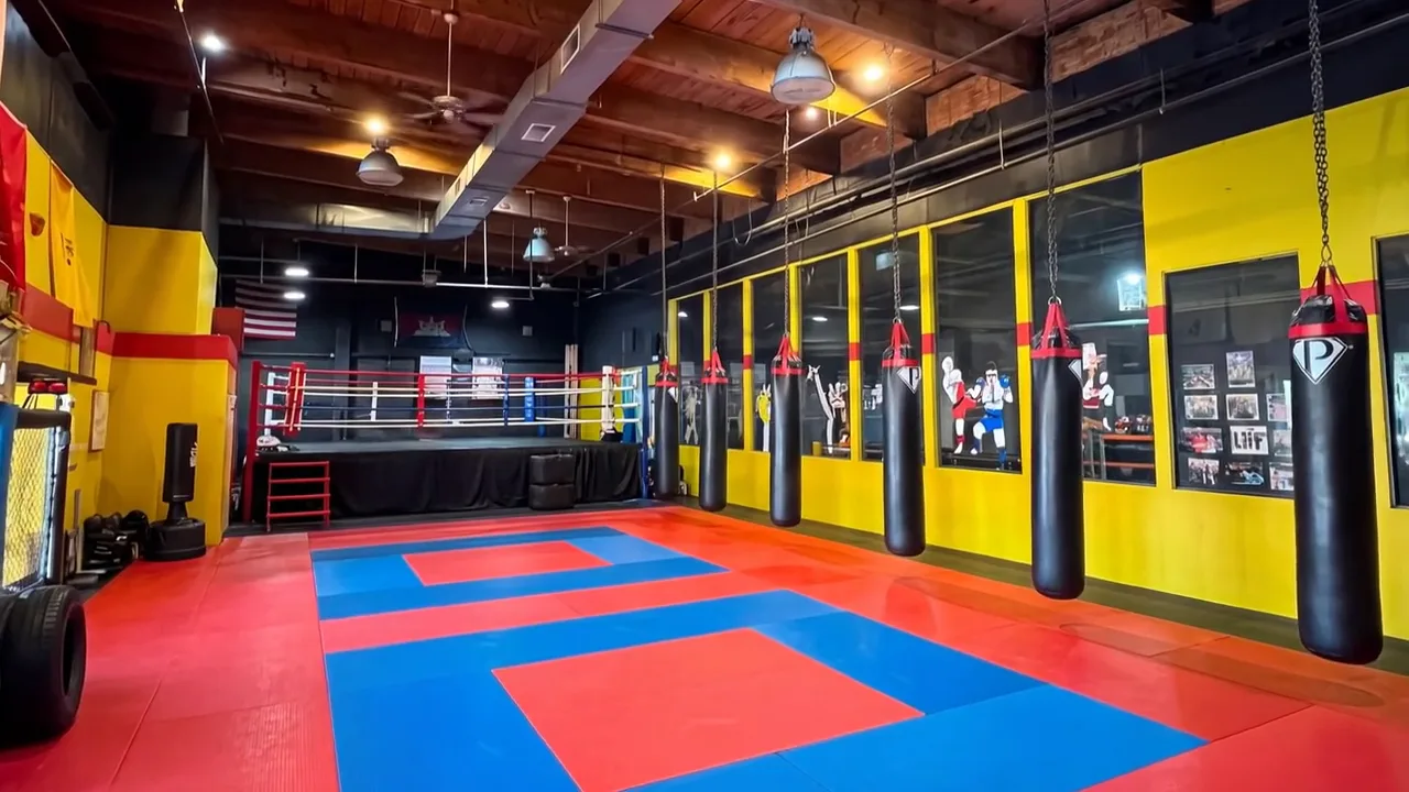 The training floor at South Sound Martial Arts, heavy bags along the mirrored wall and the ring at the far end