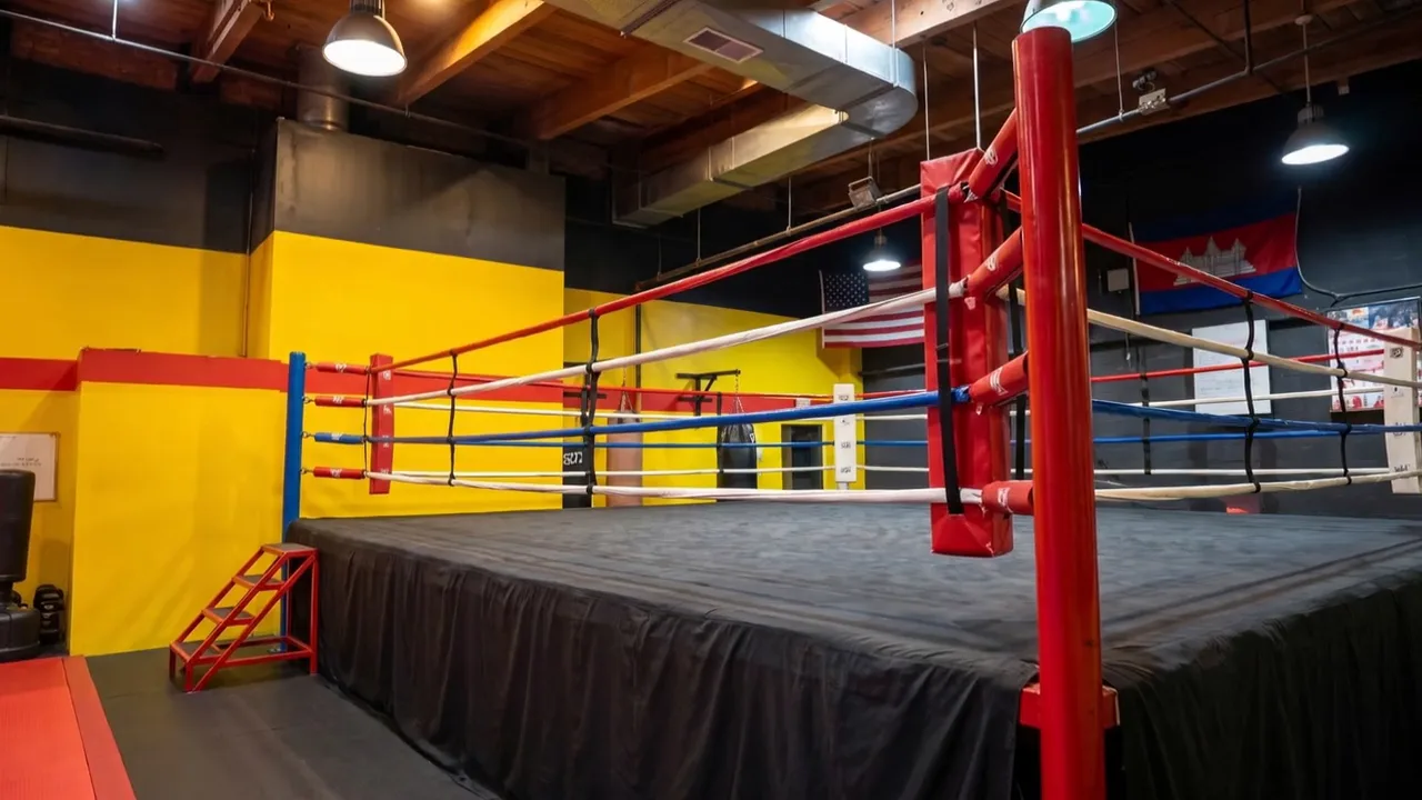 The gym's boxing ring, with the Cambodian and American flags on the wall behind it